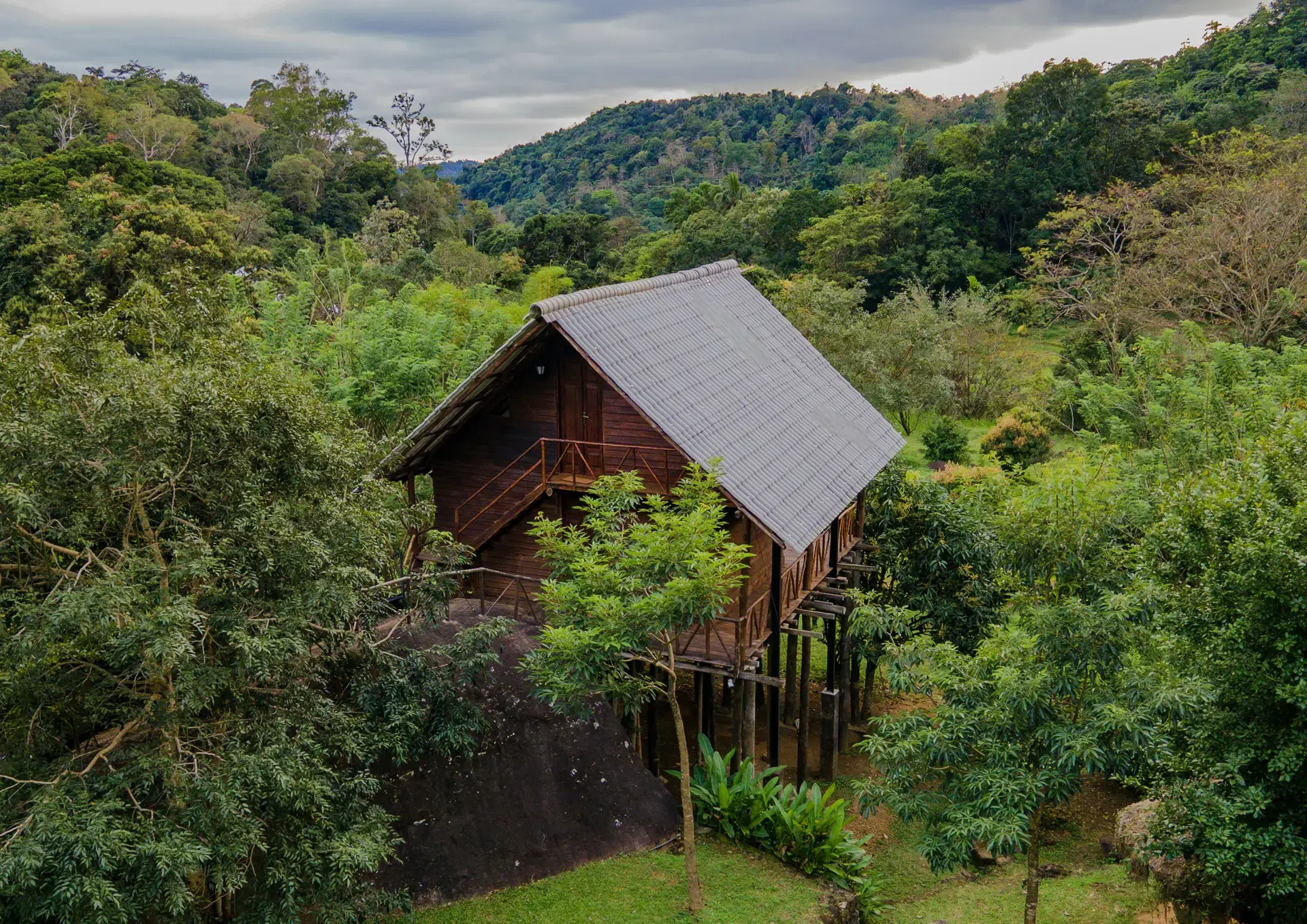 The Treehouse on its stilts beside a granite boulder, surrounded by forest