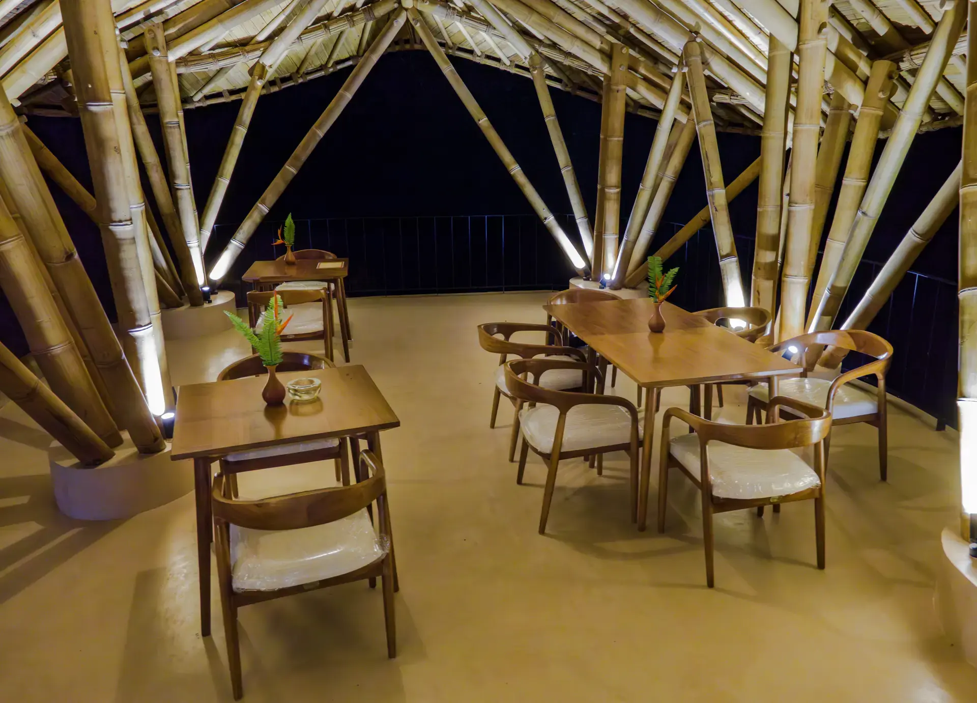 Small tables under the lantern-lit bamboo roof